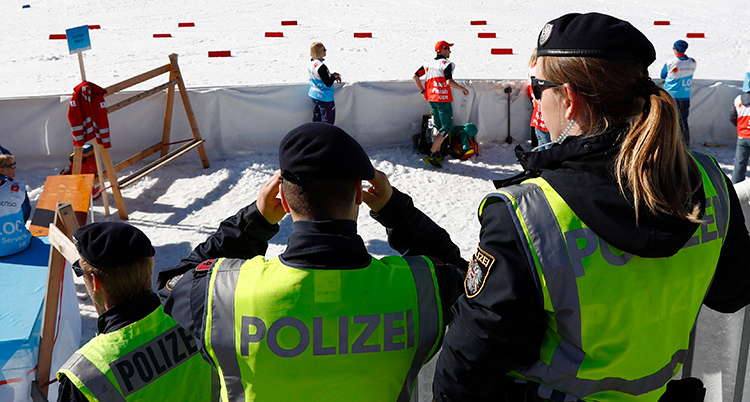 Tre poliser med gula västar tittar på skidspår.