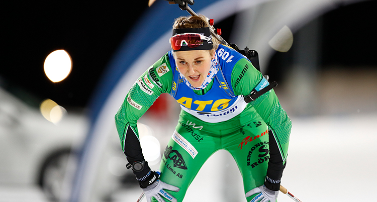 Stina Nilsson har grön dräkt. Hon har precis gått i mål. Hon lutar sig på knäna och ser trött ut.