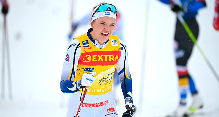 Hon åker skidor i vit dräkt och en vit mössa