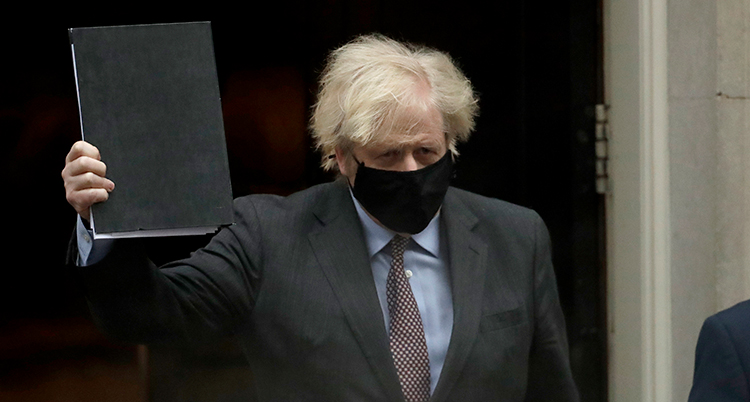 Boris Johnson med vild frisyr och munskydd håller upp en svart pärm.