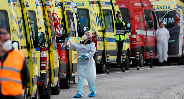 En vårdpersonal står utanför en av ambulanserna som väntar på gatan.