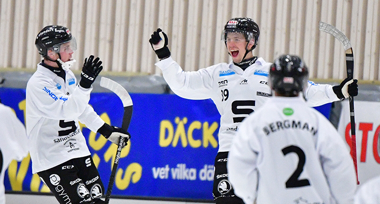 Glada spelare i vita dräkter och svarta hjälmar. De jublar efter ett mål.