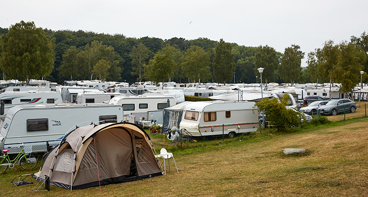 En campingplats full med husvagnar och ett tält längst fram i bilden.