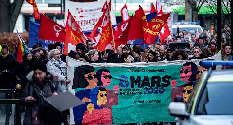De går i ett demonstrationståg med flaggor och banderoller.