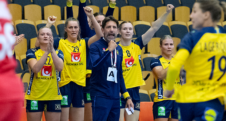 Axnér står i mittenav bilden i blå kläder. Runt om honom står svenskaq spelare med gula dräkter. En del av dem sträcker armarna i luften.