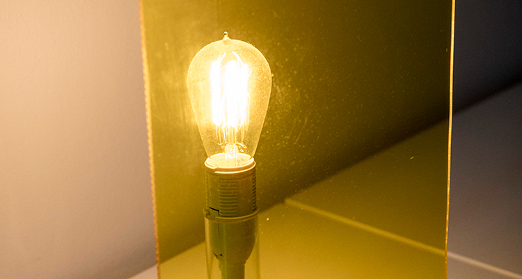 En glödlampa bakom en gul plastskiva lyser