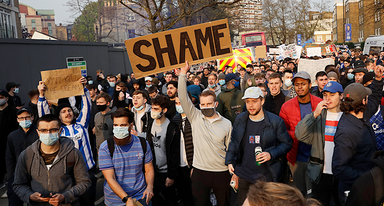 En bild från staden London. Många unga män har samlats ute på gatan. De protesterar. Flera av dem har plakat med sig.