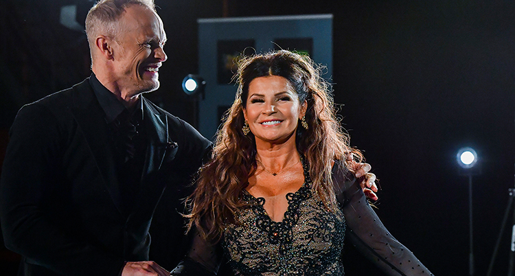 Carola ler mot kameran. Bredvid står Tobias och tittar på henne.