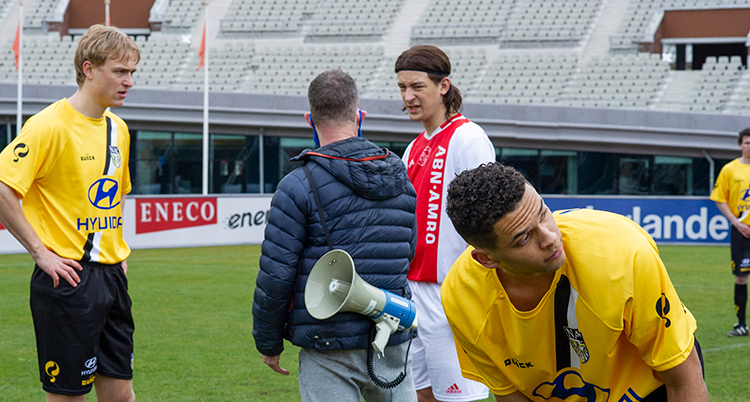 Flera personer i fotbollskläder står på en fotbollsplan.