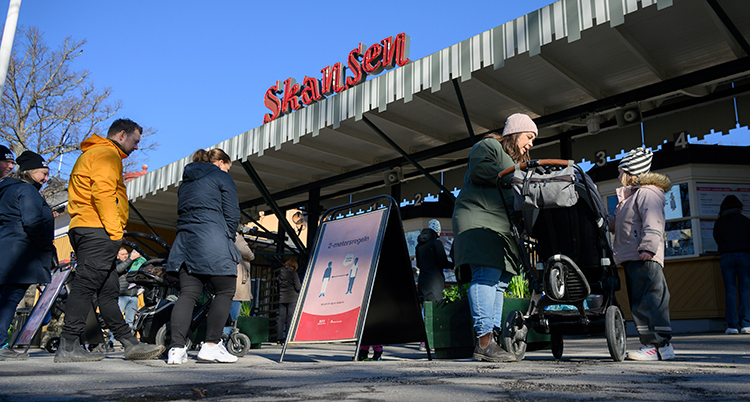 En entre med ett tak där det står Skansen med röda bokstäver. Människor är på väg in i entrén, under taket. Flera av dem är barn.