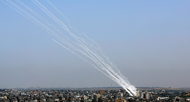 En bild på Gaza uppifrån. Från ett hus skjuts det stridsraketer. Man ser långa vita streck av rök.