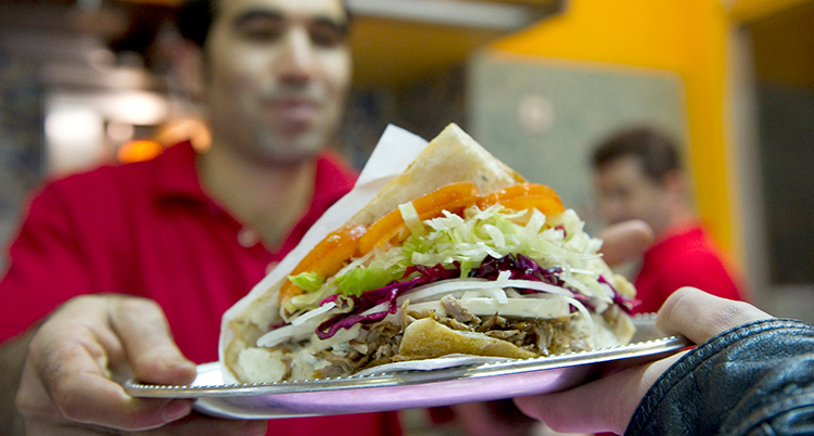 En man håller fram en kebab.
