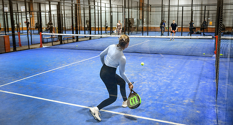 En spelare är på väg att slå en boll med sitt racket. Planen är blå.