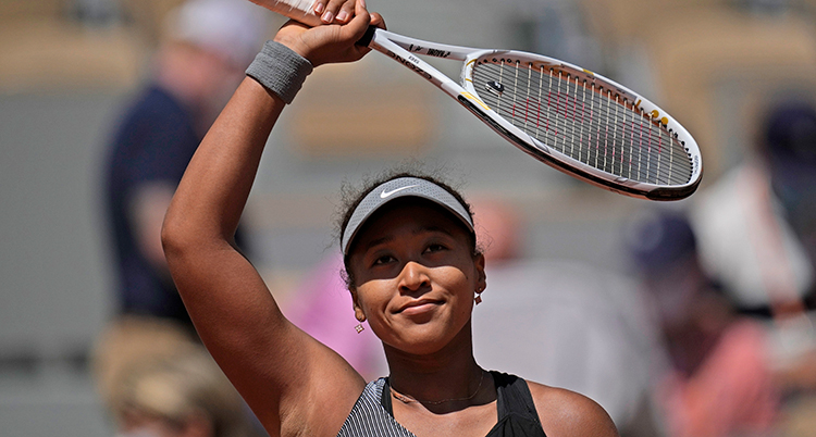 Naomi Osaka vinkar med tennisracketet mot publiken efter en tävling.