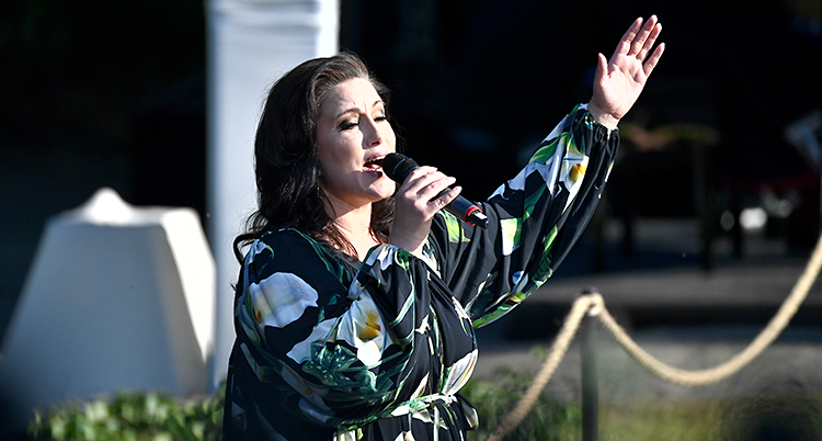 Lisa Nilsson står på en scen. Hon sjunger i en mikrofon och blundar med ögonen.