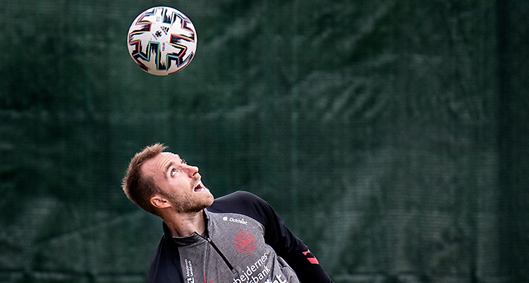 Från en träning i fotboll. Christian Eriksen nickar bollen. Bollen är i luften och han tittar på den.