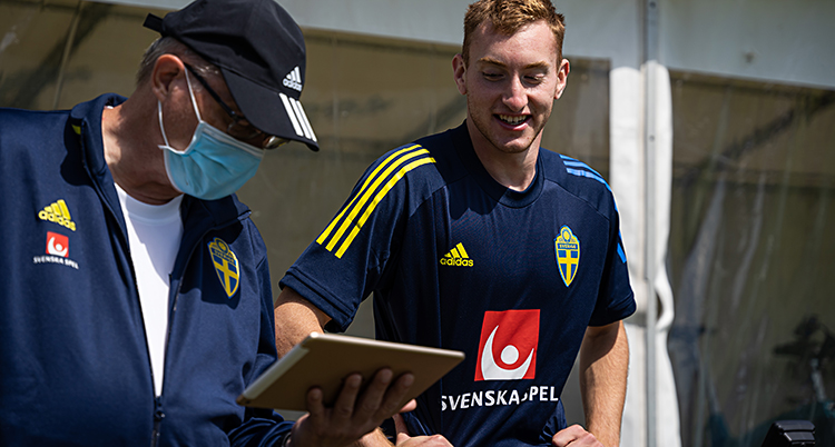 Från en träning med Sverige. Dejan Kulusevski är glad. Bredvid honom står en man med munskydd.