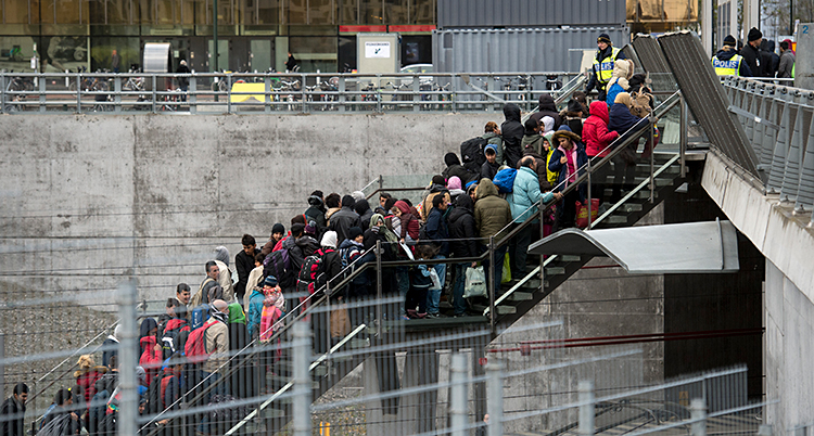Bilden är tagen vid en tågstation. Människor går uppför en trappa. Längst upp i trappan står poliser.
