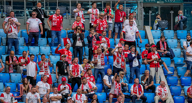 Människor sitter på en läktare och tittar på en match.
