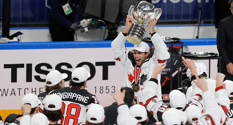Spelare i vita dräkter samlas runt en spelare som lyfter en pokal över huvudet. Foto: TT