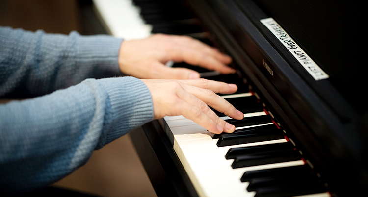 Två händer spelar på ett piano.