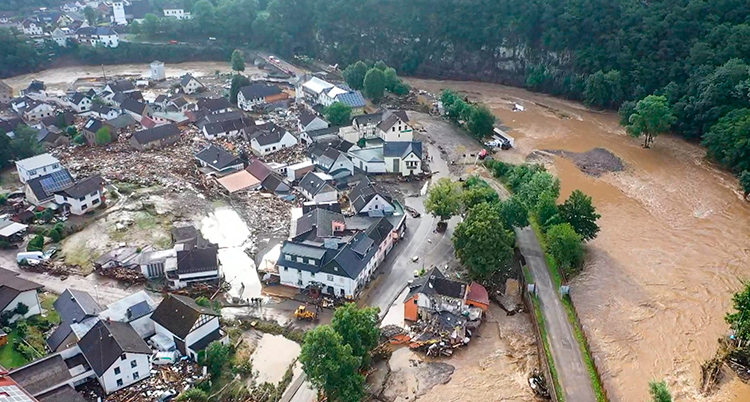 En bild av staden tagen från luften. Brunt vatten breder ut sig runt staden och bland husen.