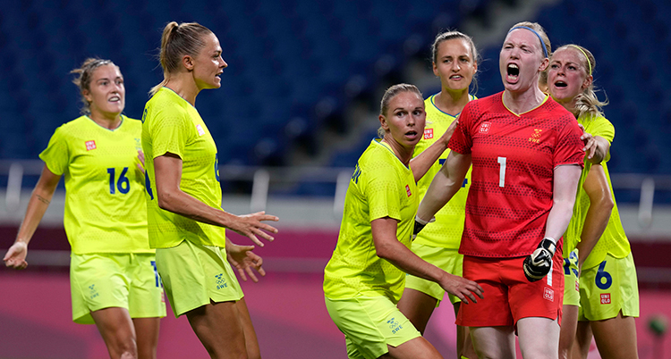 Fler fotbollsspelare i gula tröjor rör sig mot målvakten i röd tröja. Målvakten skriker.