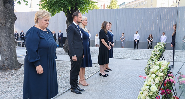 Fem personer står framför blomsterkransar som är uppsatta på ställningar.