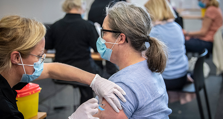 En kvinna får vaccination i armen av en annan kvinna.