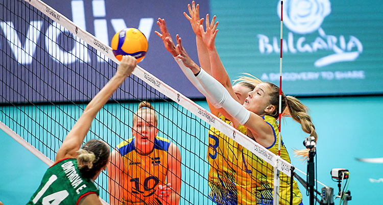 Från en match i volleyboll. De svenska spelarna hoppar och försöker stoppa en boll vid nätet.