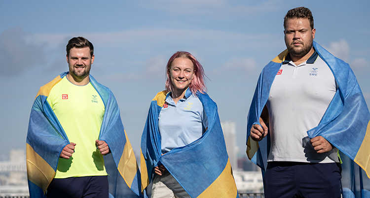De tre medaljörerna står bredvid varandra. Alla har en svensk flagga över axlarna. Sarah Sjöström står i mitten.