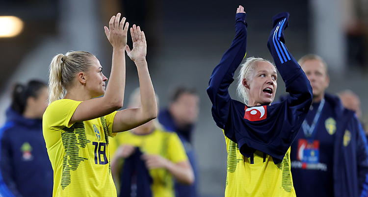 De står på fotbollsplanen och tackar publiken genom att klappa händerna.