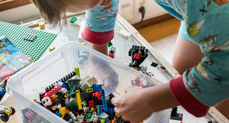 Barnet plockar med handen i en plastlåda med lego