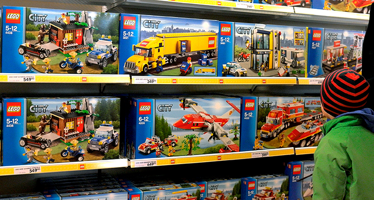Ett barn tittar på hyllor med förpackningar med lego.