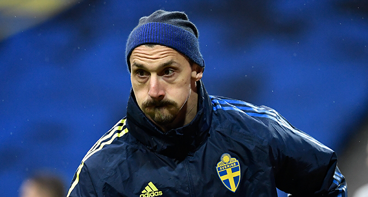 Zlatan Ibrahimovic tränar med Sveriges lag på en fotbollsplan. Han har jacka och mössa på sig.