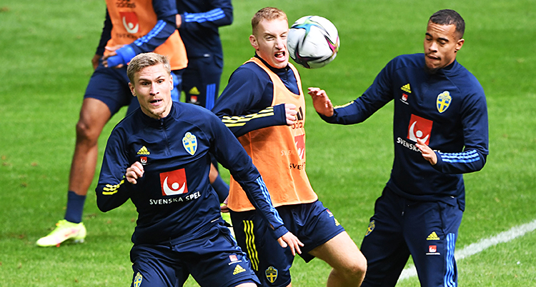 Från en träning i fotboll. Tre spelare kämpar om bollen.