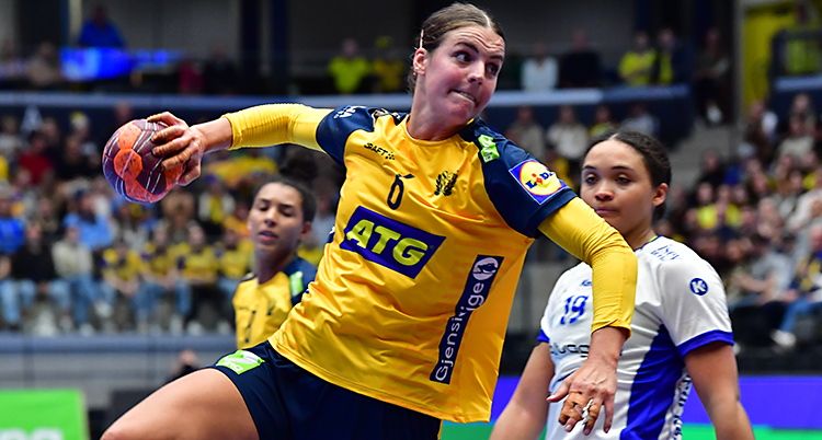 Från en match i handboll. En svensk spelare hoppar för att skjuta. Hon har bollen i handen.