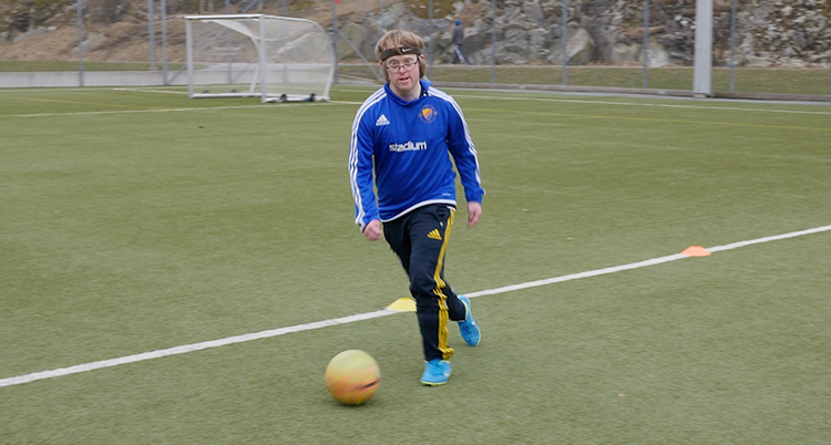 Han spelar fotboll på en plan