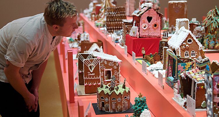 En kille står och tittar på pepparkakshusen.