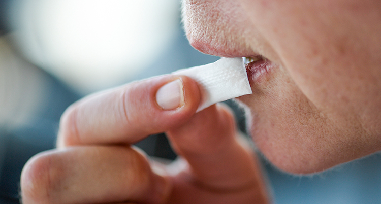 En kvinna stoppar in en snus under läppen.