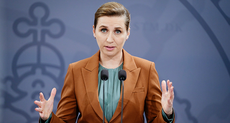 Mette Frederiksen pratar och viftar med händerna på presskonferensen.