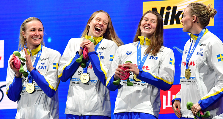 De fyra står intill varandra med medaljer runt halsen och skrattar