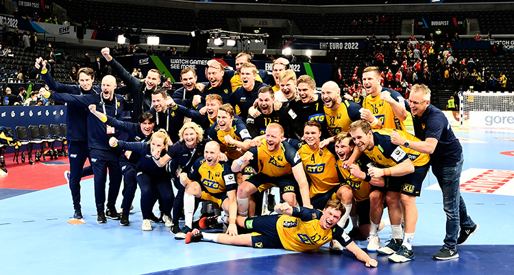 Hela laget står och sitter i en hög på planen. Alla är glada
