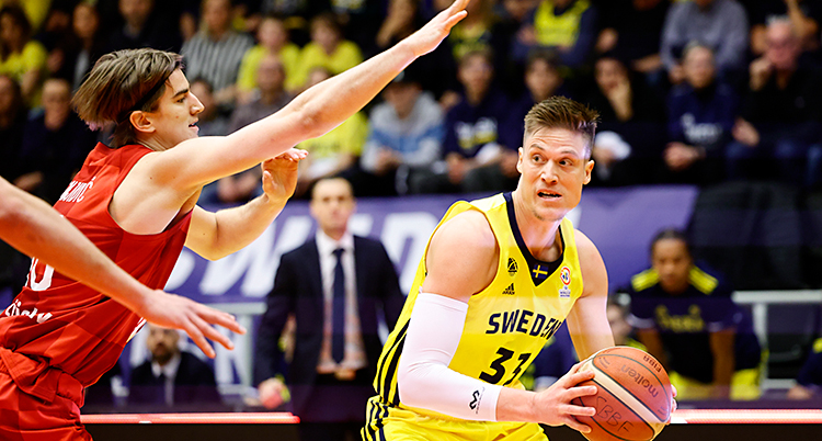 Från en match i basket. Jonas Jerebko försöker ta sig fram med bollen förbi en motspelare.