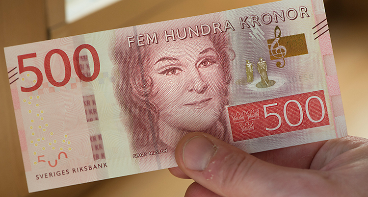 En hand håller i en sedel som är värd 500 kronor.