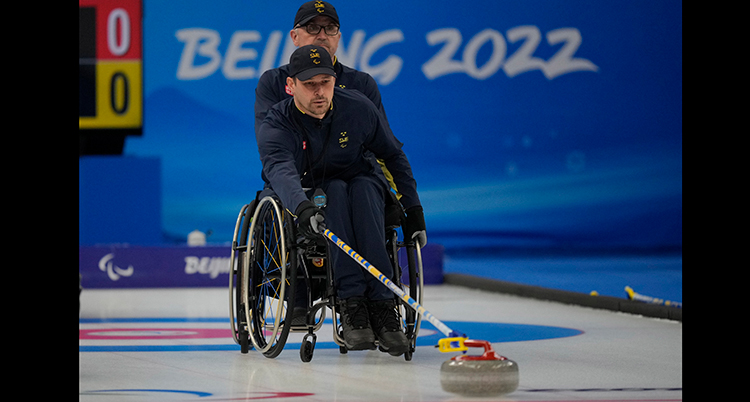 En man i rullstol skjuter iväg en curlingsten.