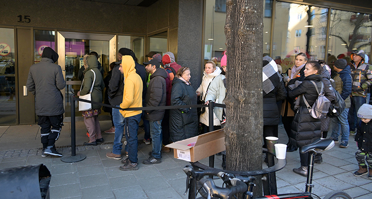 Kö med människor ute på gatan och väntar på att gå in.