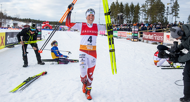 Kalla håller upp skidor och stavar i luften och skrattar.