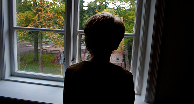 En person tittar ut genom ett fönster. Bara ryggen på personen syns.