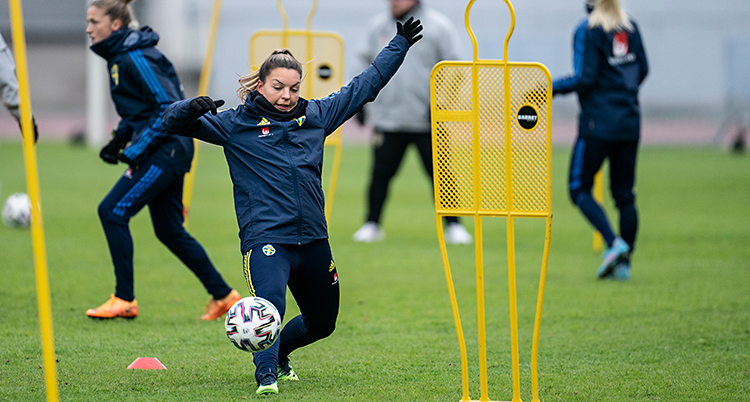 Från en träning i fotboll. Flera spelare är på en plan. Närmast i bilden är en spelare med en boll.